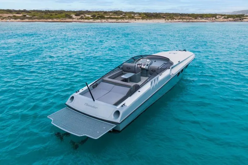  Yacht Photos Pics Luxury Magnum 44 boat from 2003 on clear turquoise water near a sandy shore.