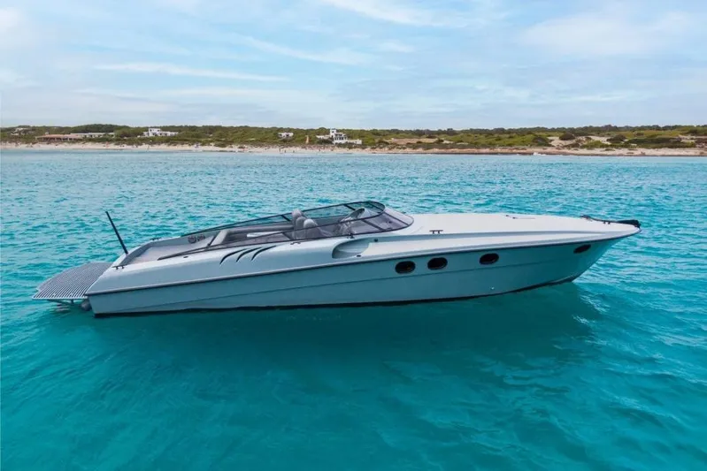  Yacht Photos Pics 2003 Magnum 44 boat on turquoise water near a sandy shoreline.