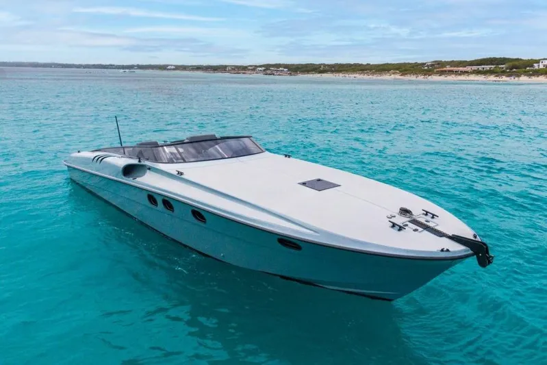  Yacht Photos Pics 2003 Magnum 44 boat on clear turquoise water near a sandy coastline.