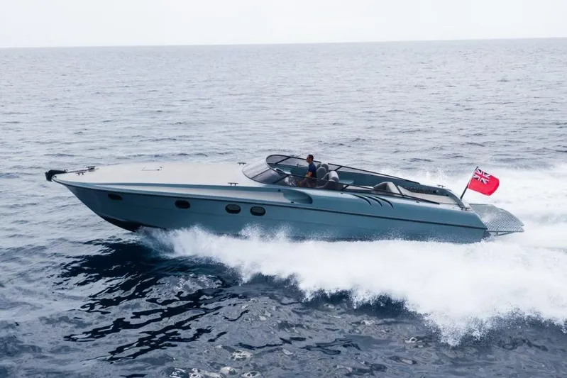  Yacht Photos Pics 2003 Magnum 44 speedboat cruising on open sea with a red flag.