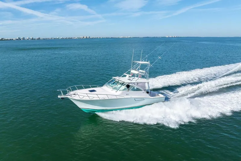 Miss B Havin Yacht Photos Pics 2005 Cabo 40 Express yacht cruising on open water under clear blue skies.