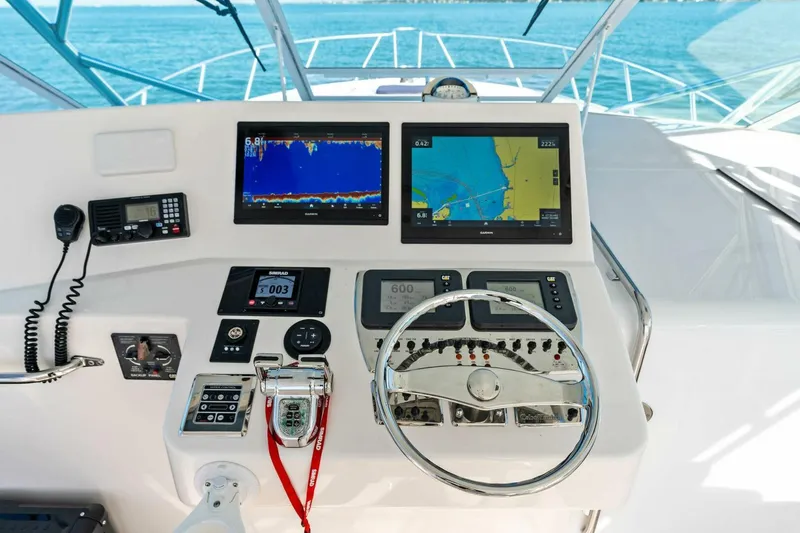 Miss B Havin Yacht Photos Pics Control panel of 2005 Cabo 40 Express boat with navigation screens and steering wheel.