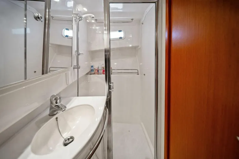 Miss B Havin Yacht Photos Pics 2005 Cabo 40 Express yacht bathroom with sink, shower, and wooden door.