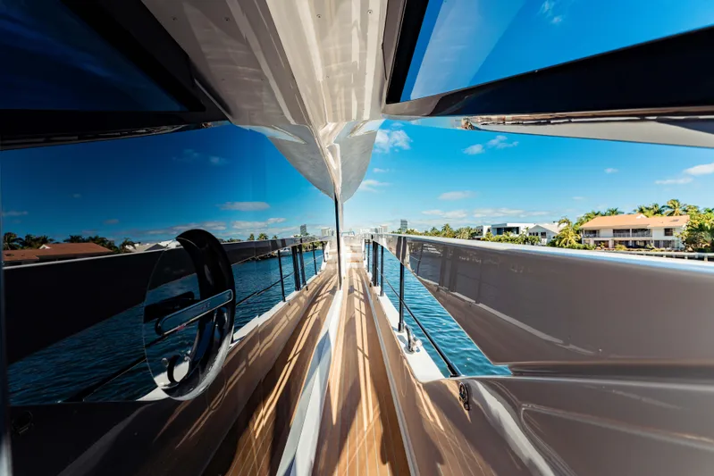  Yacht Photos Pics 2023 Ferretti Yachts 860, sleek deck view with reflections, clear blue sky, and waterfront homes.