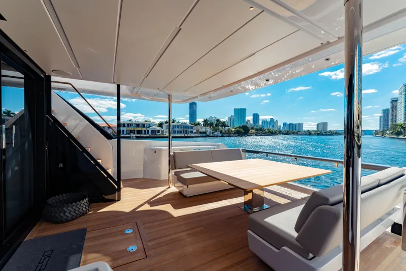  Yacht Photos Pics Luxurious 2023 Ferretti Yachts 860 deck with modern seating, overlooking scenic waterfront cityscape.
