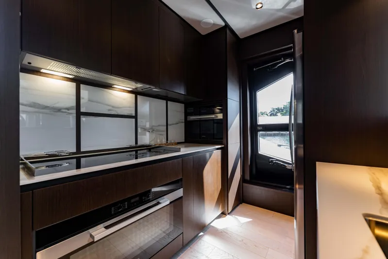  Yacht Photos Pics Luxurious kitchen interior of 2023 Ferretti Yachts 860, featuring sleek dark cabinetry and modern appliances.