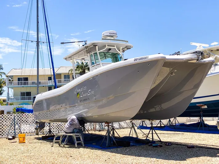  Yacht Photos Pics 2018 World Cat 320 CC boat on dry dock, undergoing maintenance in a sunny marina.