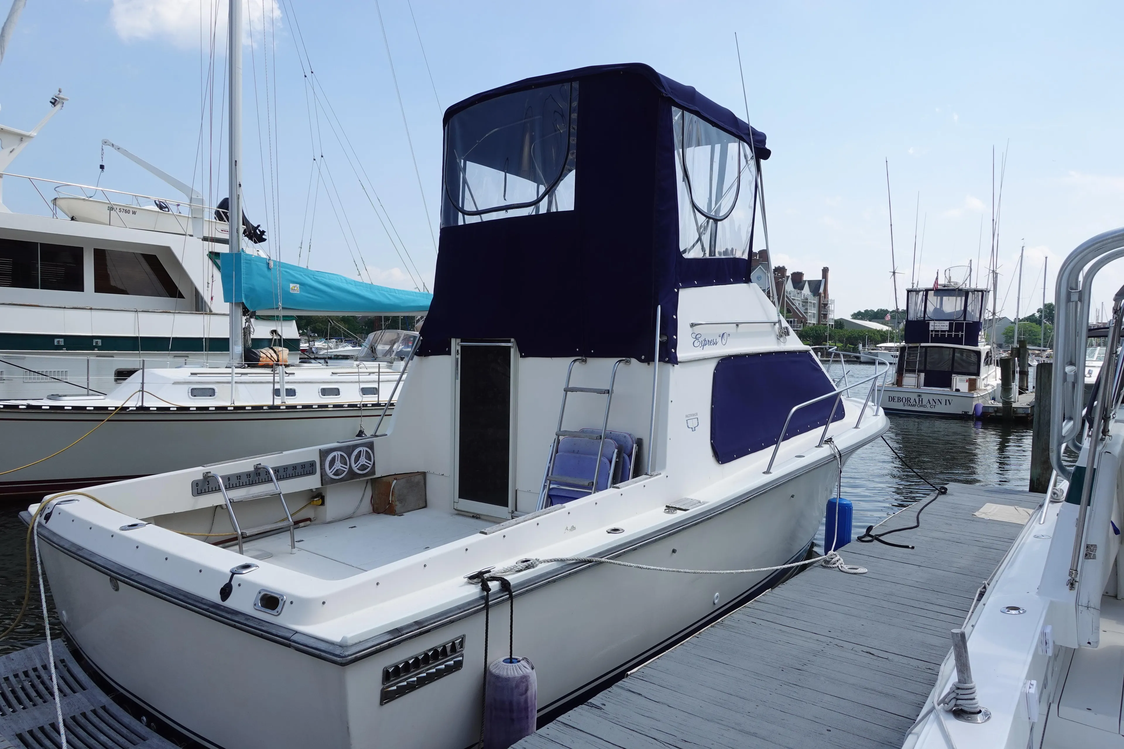 1988 Pacemaker 308 boat docked at marina, featuring blue canopy and spacious deck.