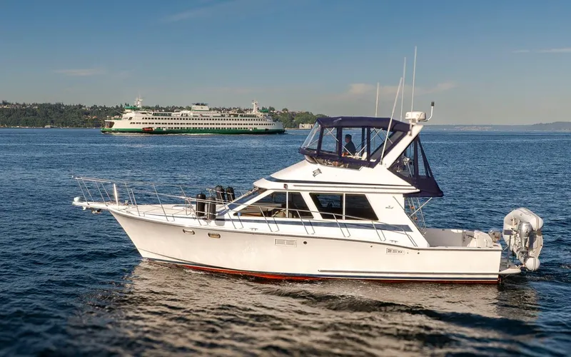 La Paz Yacht Photos Pics 1993 Tollycraft 40 Sport Sedan yacht cruising on a sunny day with a ferry in the background.
