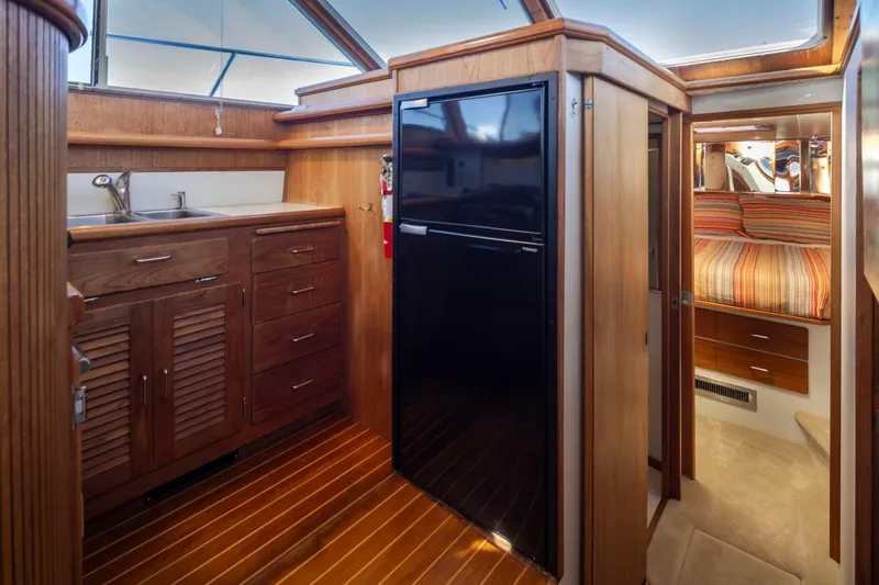 La Paz Yacht Photos Pics 1993 Tollycraft 40 Sport Sedan interior with wood cabinetry, black fridge, and cozy bedroom.