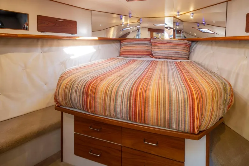 La Paz Yacht Photos Pics Cozy bedroom in 1993 Tollycraft 40 Sport Sedan with striped bedding and wooden storage drawers.