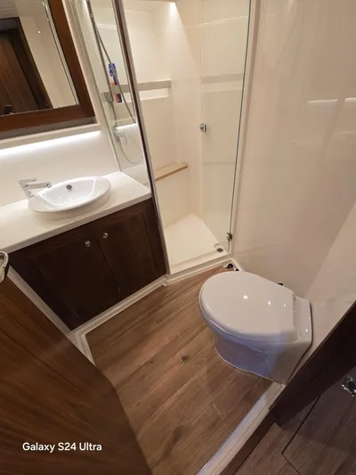 Ocean Driver Yacht Photos Pics 2022 Riviera 54 Enclosed Flybridge bathroom with modern fixtures and wooden flooring.