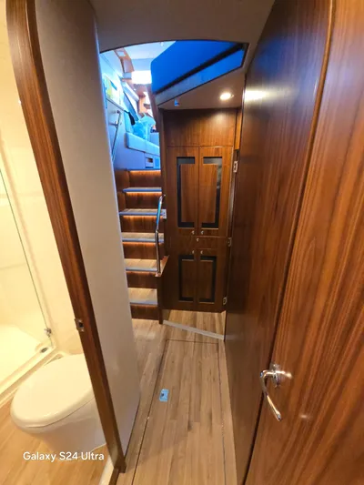 Ocean Driver Yacht Photos Pics Interior of 2022 Riviera 54 Enclosed Flybridge with wooden finishes and staircase.