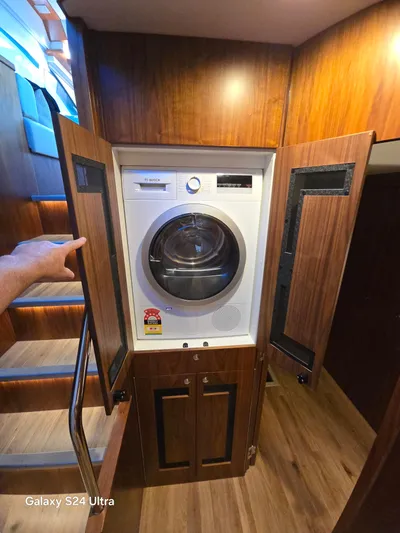 Ocean Driver Yacht Photos Pics Laundry area inside 2022 Riviera 54 Enclosed Flybridge yacht with wooden cabinetry.