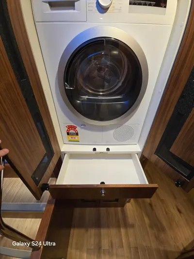 Ocean Driver Yacht Photos Pics 2022 Riviera 54 Enclosed Flybridge laundry area with washer-dryer and open storage drawer.