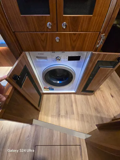 Ocean Driver Yacht Photos Pics 2022 Riviera 54 Enclosed Flybridge interior with built-in washing machine and wooden cabinetry.