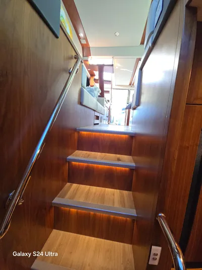 Ocean Driver Yacht Photos Pics Interior stairs of 2022 Riviera 54 Enclosed Flybridge yacht, featuring wooden finish and modern design.