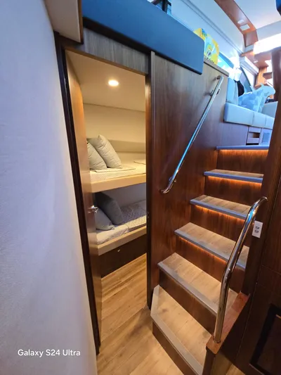 Ocean Driver Yacht Photos Pics 2022 Riviera 54 Enclosed Flybridge interior with wooden stairs and cozy bunk beds.
