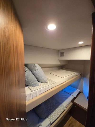 Ocean Driver Yacht Photos Pics Interior of 2022 Riviera 54 Enclosed Flybridge with cozy bunk beds and soft lighting.
