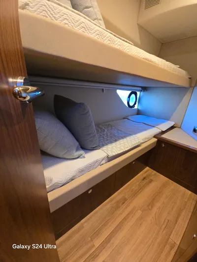 Ocean Driver Yacht Photos Pics Interior cabin of 2022 Riviera 54 Enclosed Flybridge with bunk beds and wooden flooring.