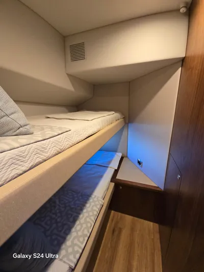 Ocean Driver Yacht Photos Pics Interior of 2022 Riviera 54 Enclosed Flybridge with cozy bunk beds and wooden accents.
