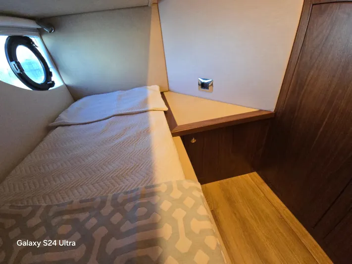 Ocean Driver Yacht Photos Pics 2022 Riviera 54 Enclosed Flybridge cabin interior with bed and porthole window.