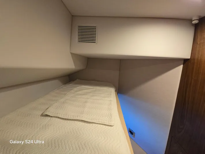 Ocean Driver Yacht Photos Pics Interior cabin of 2022 Riviera 54 Enclosed Flybridge yacht, featuring a cozy bed.