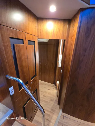 Ocean Driver Yacht Photos Pics Interior of 2022 Riviera 54 Enclosed Flybridge with wooden finishes and modern lighting.
