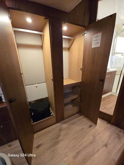 Ocean Driver Yacht Photos Pics Interior view of 2022 Riviera 54 Enclosed Flybridge wardrobe with open wooden doors.