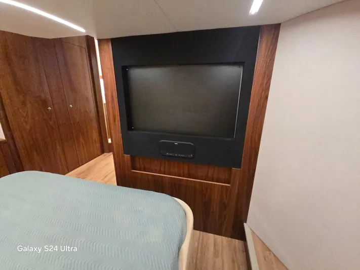 Ocean Driver Yacht Photos Pics Interior of 2022 Riviera 54 Enclosed Flybridge with wood paneling and a mounted TV.