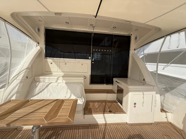 Ocean Driver Yacht Photos Pics 2022 Riviera 54 Enclosed Flybridge interior with teak flooring and modern seating area.