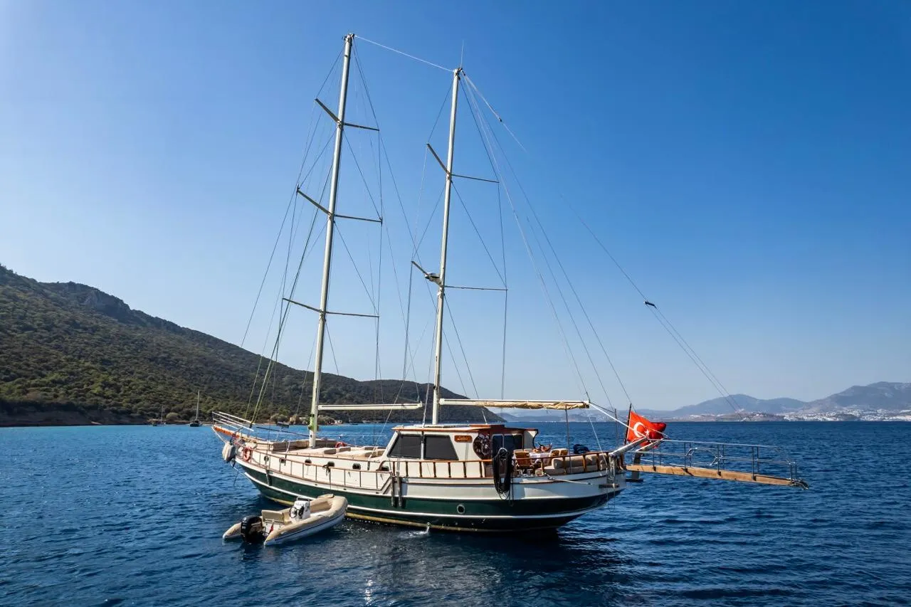 Sailing yacht with two masts anchored in a serene bay, 1990 custom model.