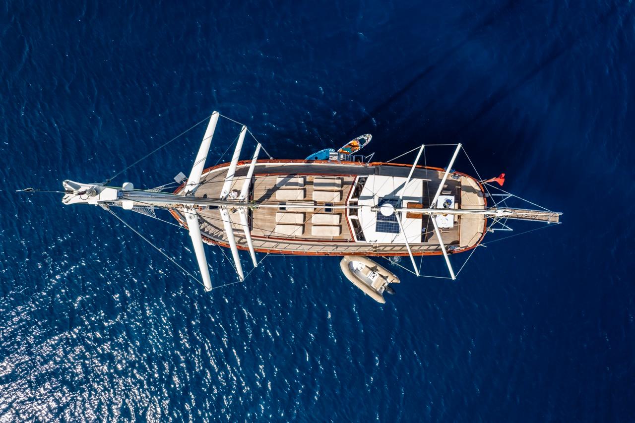 Aerial view of a custom 1990 sailboat on deep blue ocean water.