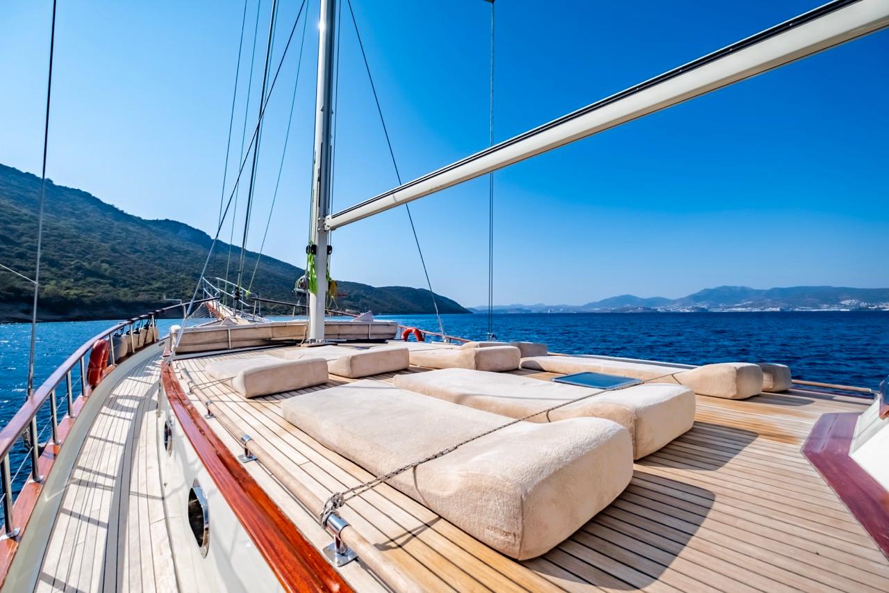 Luxurious yacht deck with sun loungers, surrounded by blue sea and distant mountains.