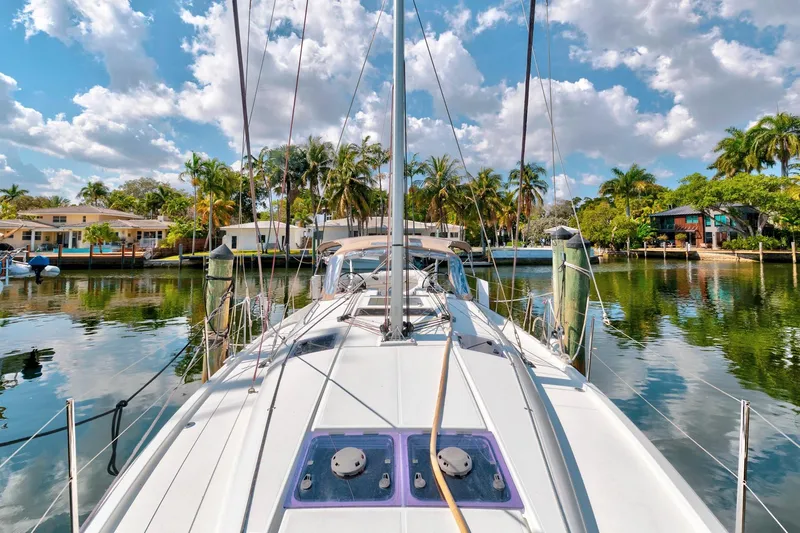 Dantari Yacht Photos Pics 2021 Jeanneau Sun Odyssey 440 sailboat docked in a tropical marina with palm trees.