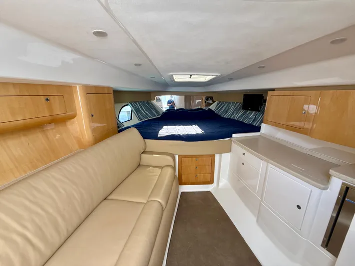  Yacht Photos Pics 2013 Intrepid 390 Sport Yacht interior with beige seating, wooden cabinets, and a cozy bed.