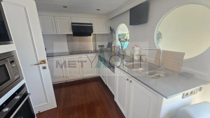  Yacht Photos Pics Modern kitchen interior on 2010 Ses Yachts 100, featuring white cabinetry and round windows.