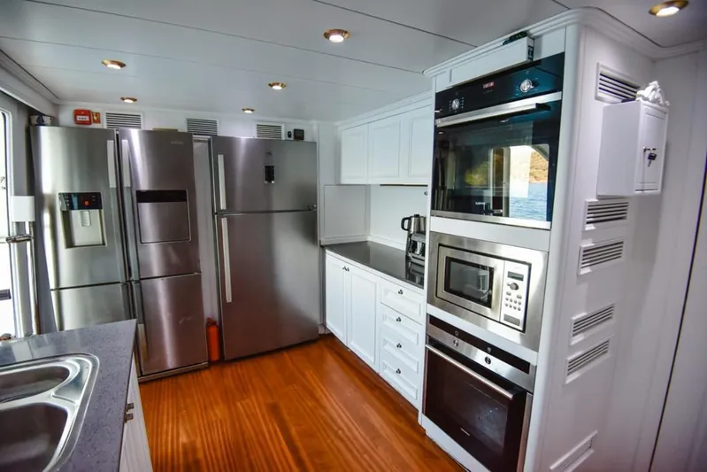  Yacht Photos Pics Luxurious yacht kitchen with modern appliances, stainless steel fridge, and wooden flooring on Ses Yachts 100.