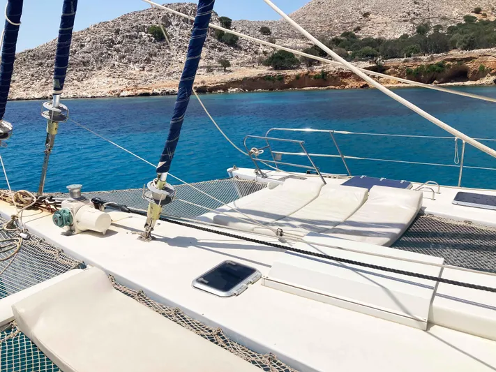 Conan Yacht Photos Pics 1988 Joubert Custom Trimaran anchored in a serene bay with clear blue water.