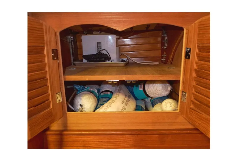  Yacht Photos Pics Open wooden cabinet on 1983 Valiant 40 Selah, storing various supplies and equipment.