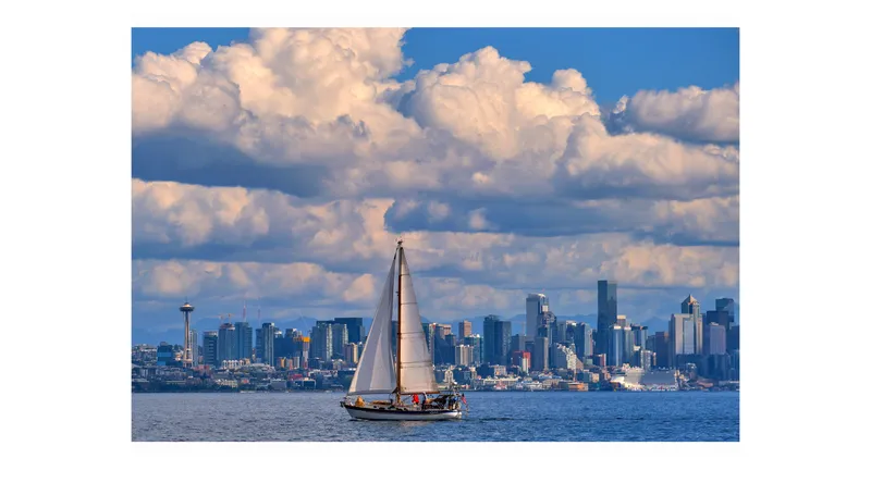  Yacht Photos Pics Sailboat Valiant 40 Selah on water with city skyline and clouds in background.