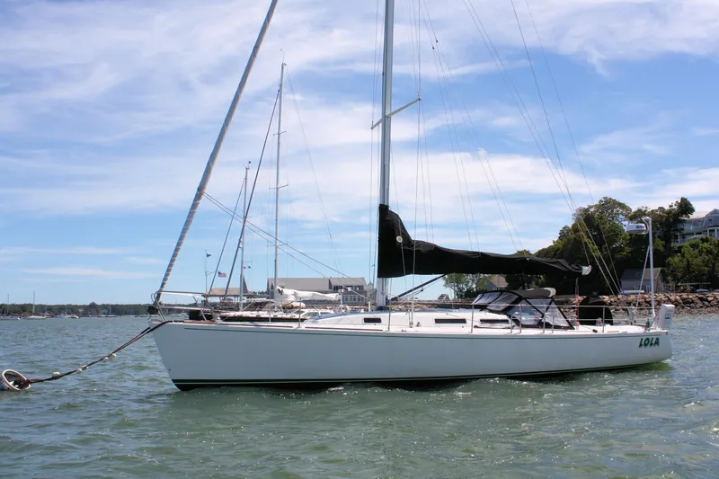 Lola Yacht Photos Pics 1995 J Boats J/130 sailboat anchored in a scenic harbor under a clear blue sky.