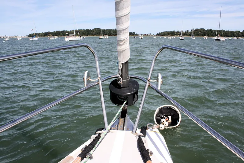 Lola Yacht Photos Pics Bow view of 1995 J Boats J/130 sailboat on a calm sea with moored boats.