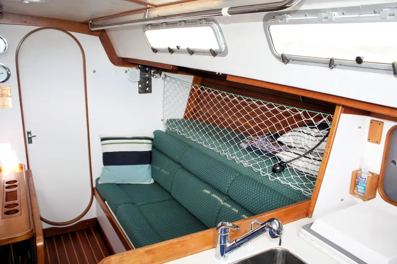 Lola Yacht Photos Pics Cozy interior of 1995 J Boats J/130 sailboat with green seating and net storage.