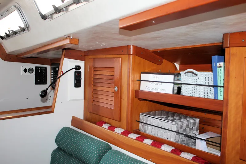 Lola Yacht Photos Pics Interior of 1995 J Boats J/130 with wooden shelves and manuals.