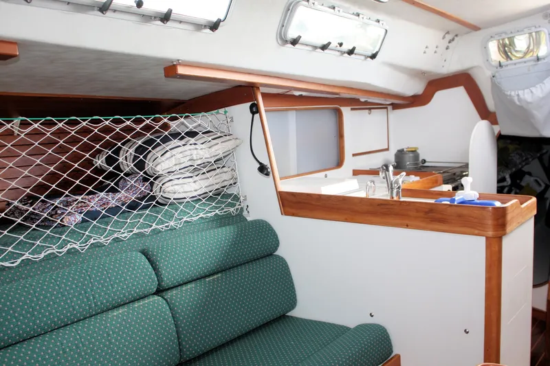 Lola Yacht Photos Pics Interior of 1995 J Boats J/130 sailboat with green seating and compact kitchen area.