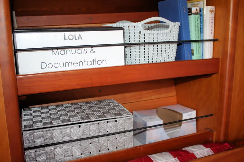 Lola Yacht Photos Pics Shelf with manuals, books, and baskets on a 1995 J Boats J/130 sailboat.