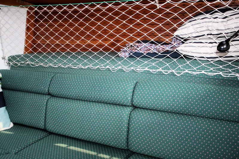 Lola Yacht Photos Pics Interior of 1995 J Boats J/130 with green cushioned seating and storage netting.