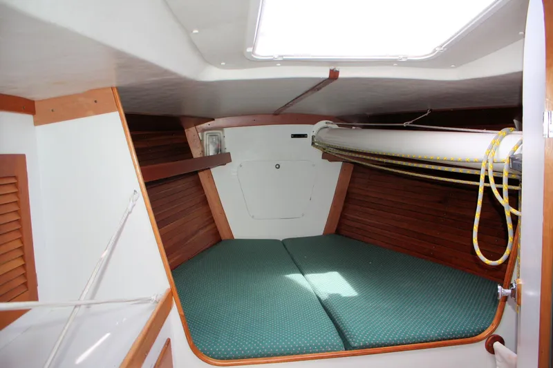 Lola Yacht Photos Pics Interior cabin of 1995 J Boats J/130 sailboat with wooden accents and green cushions.