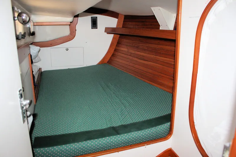 Lola Yacht Photos Pics 1995 J Boats J/130 cabin interior with green mattress and wooden paneling.
